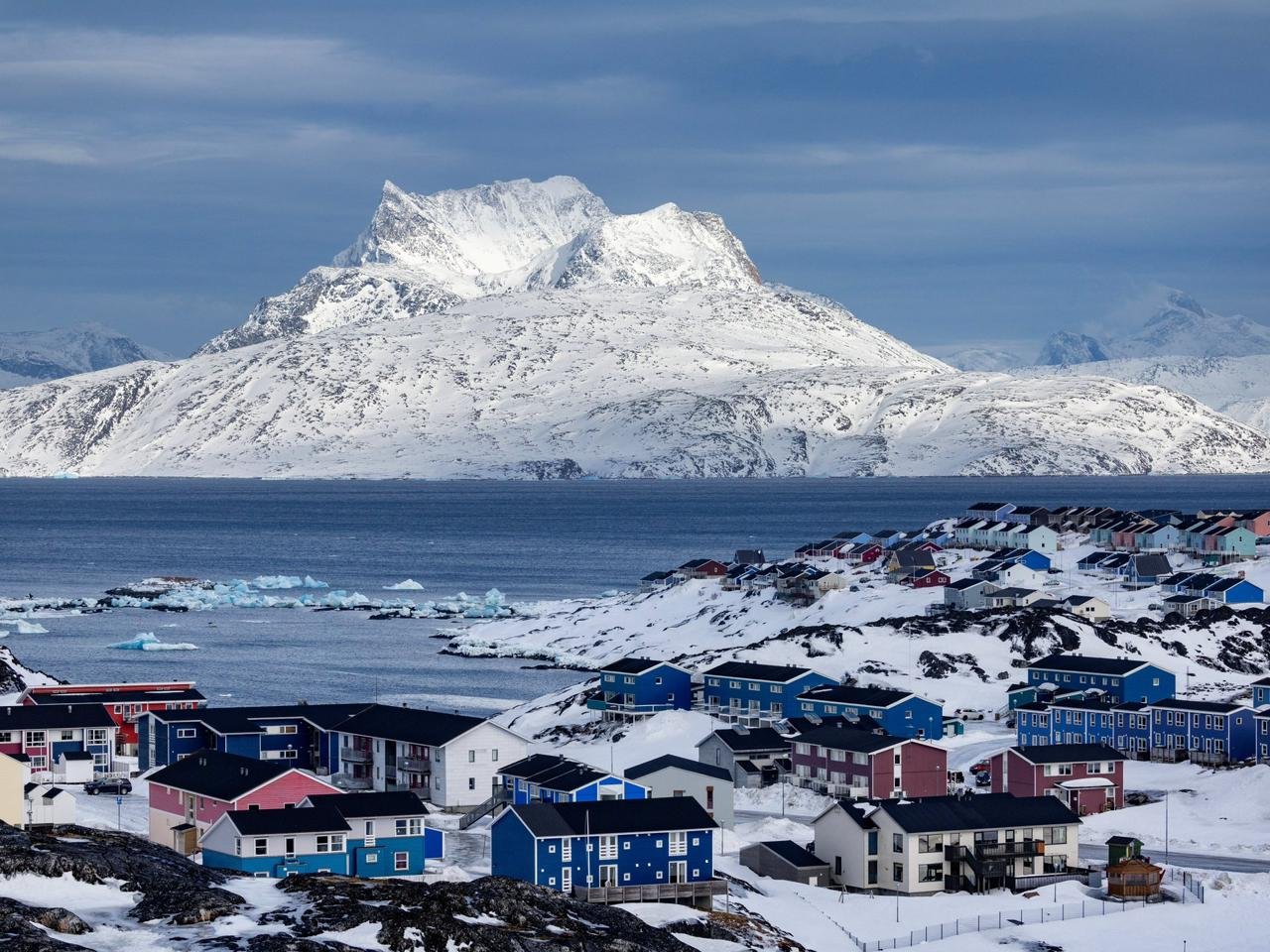 بلدة غرينلاندية ملونة على ساحل ثلجي وجبال مغطاة بالثلج